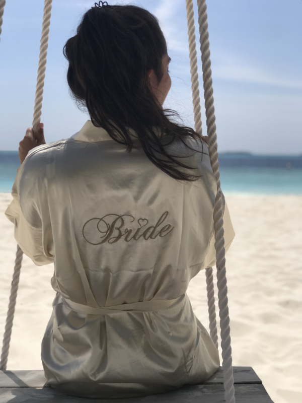 Vrouw op het strand met de champagne kimono in een schommel