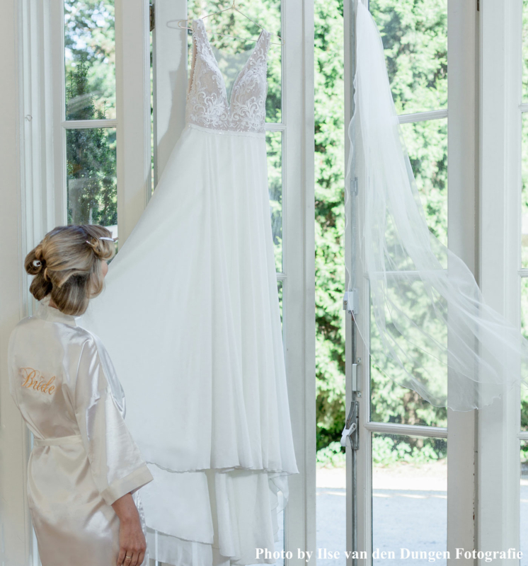 Bruid in witte drks kimono kijkt naar bruidsjurk