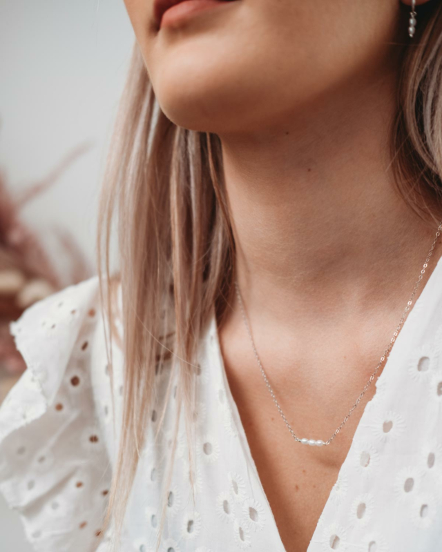 Vrouw draagt parelketting met drie pareltjes