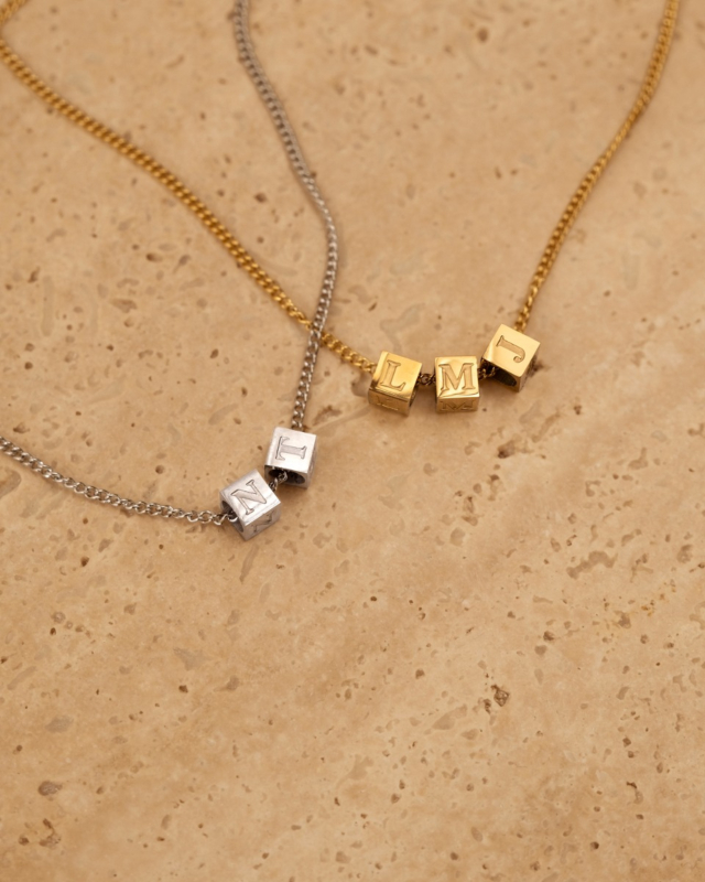 zilveren en gouden initial cube ketting op stenen ondergrond