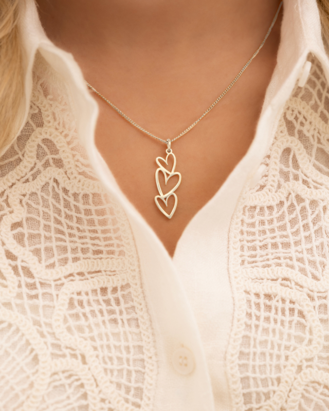 Model draagt zilveren ketting triple heart