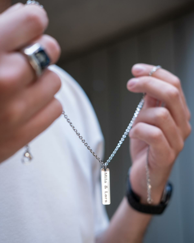 Het model draagt de gepersonaliseerde mannenketting in zijn handen