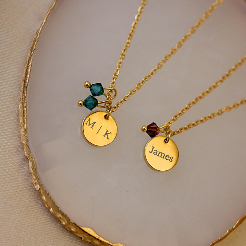 Twee birthstone kettingen op marmer in de kleur goud