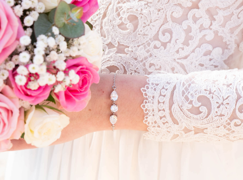 Vrouw met bloemen in bruidsjurk met mooie armband