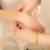 Moeder en kind dragen gouden armband met gravering om pols