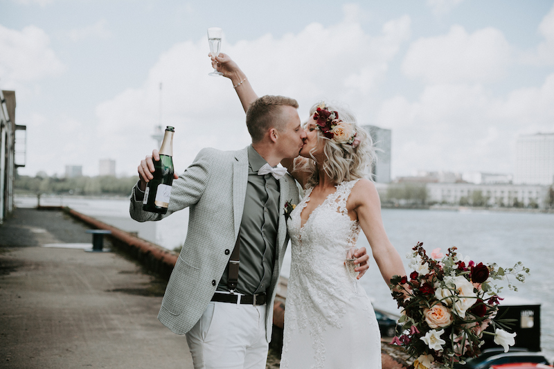 Bruidspaar met champagne bij kade